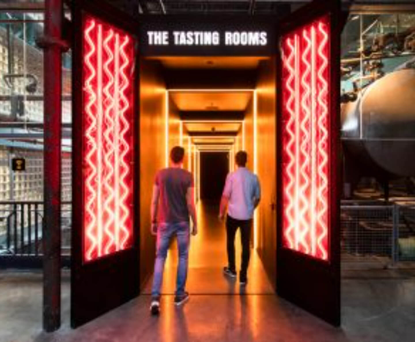 Two people entering into a neonn red room, that is the tasting rooms in guinnesses