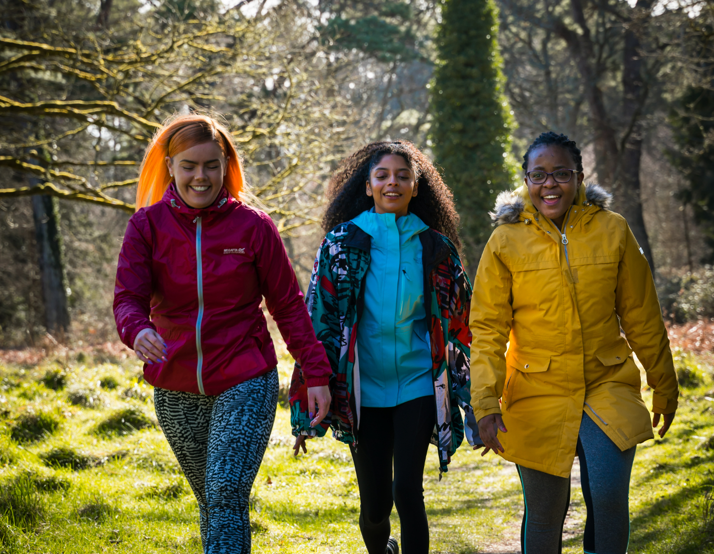 Three women walking through the forest in big coats