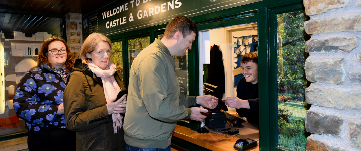 A couple at a front desk buying tickets for blarney castle