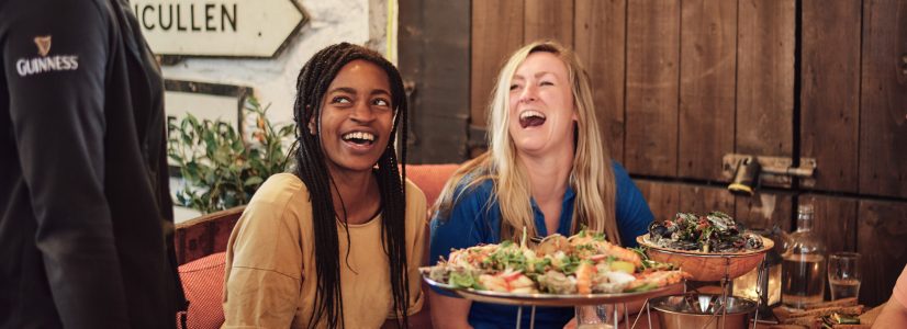 Two people smiling while talking to waiter