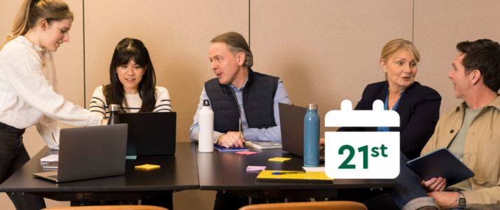 A group of people in a meeting room with a calendar that reads 21