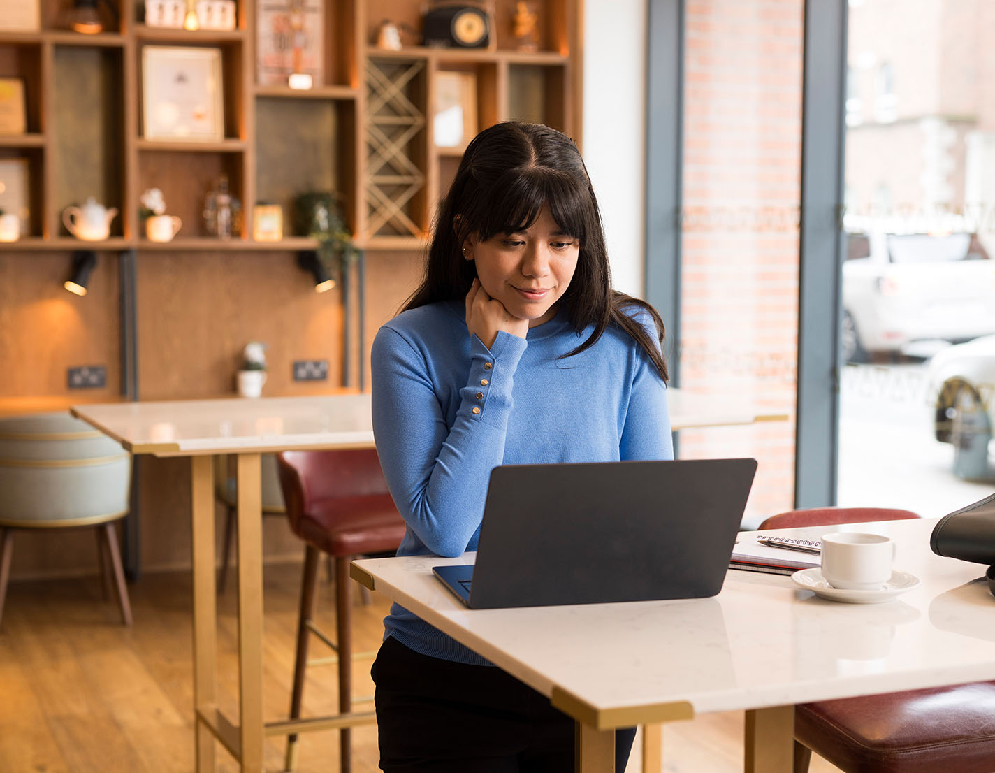 Woman smiles at laptop in cafe