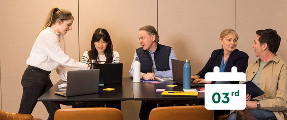 five people sitting at a table with laptops with a calendar that says 3rd