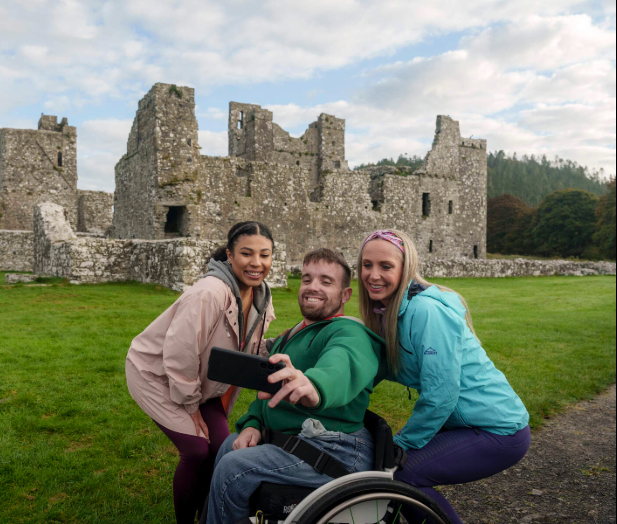 Three people outside a castle ruin taking a selfie.
