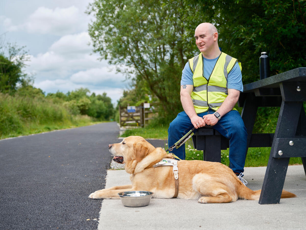 Man sitting on a bench with a guide dog