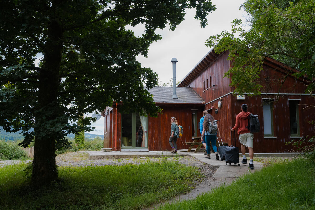 Three people with their suitcases going into a lodge