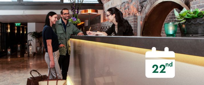 Couple speaking to hotel receptionist, calendar icon reads 22nd